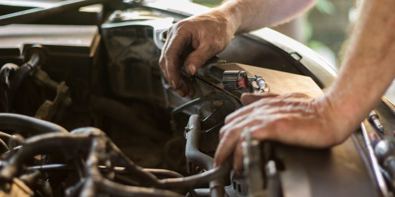 mechanic working under the hood of a car engine